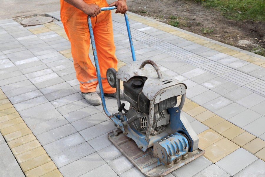 Contractor using plate compactor during ground compaction project in Garland, TX