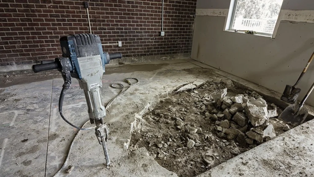 Heavy-duty jackhammer breaking up damaged concrete floor during foundation demolition in Garland, TX