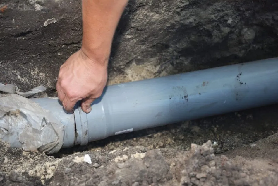 Contractor installing replacement PVC drainage pipe during underground repair in Garland, TX