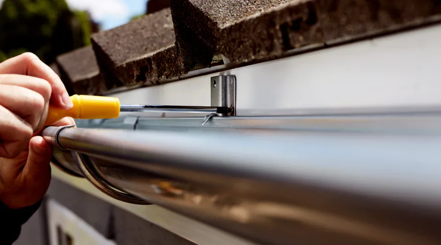 Gutter installation contractor securing brackets and downspouts in Garland, TX