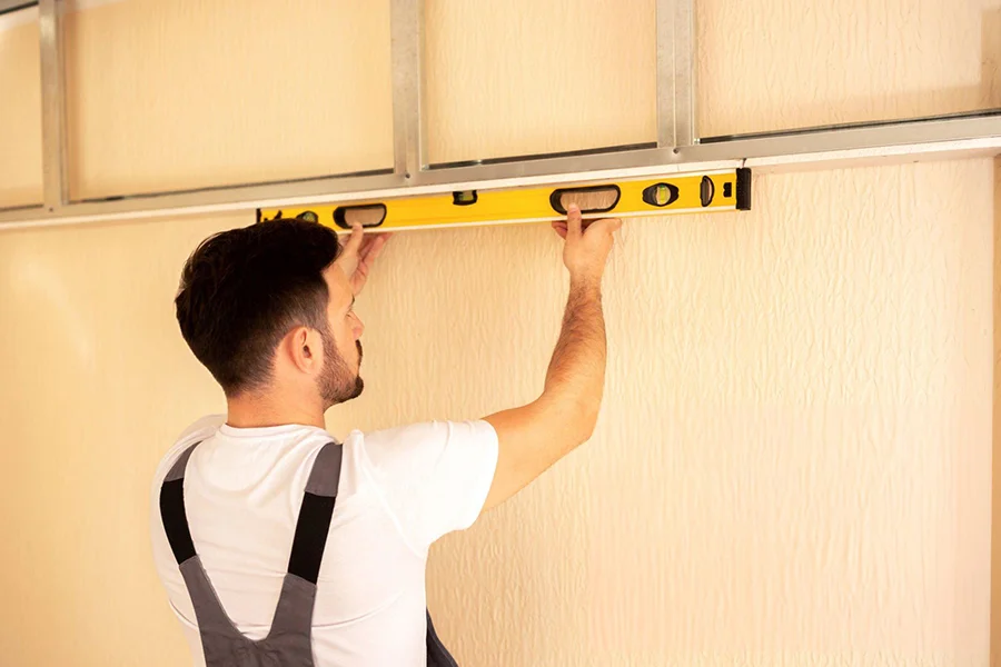 House leveling service in Garland, TX with contractor using spirit level to check ceiling alignment