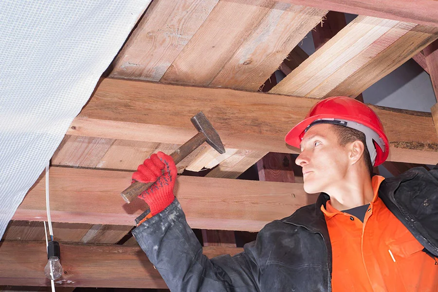 Contractor repairing wooden floor joists during house leveling project in Garland, TX