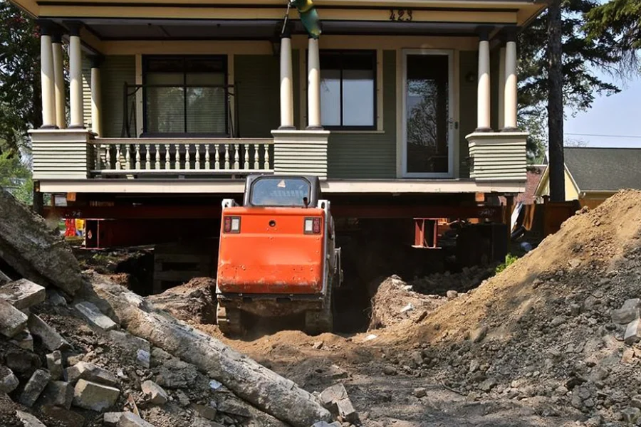 Historic home lifted during house raising project with excavator working underneath in Garland, TX