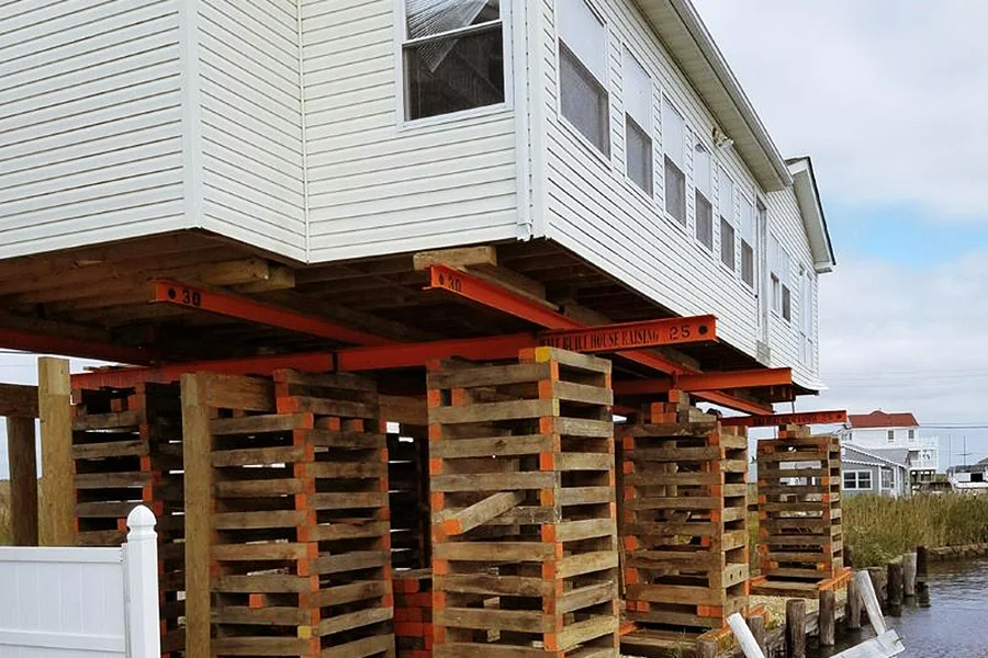House lifting service in Garland, TX with home elevated on wooden cribbing and steel support beams