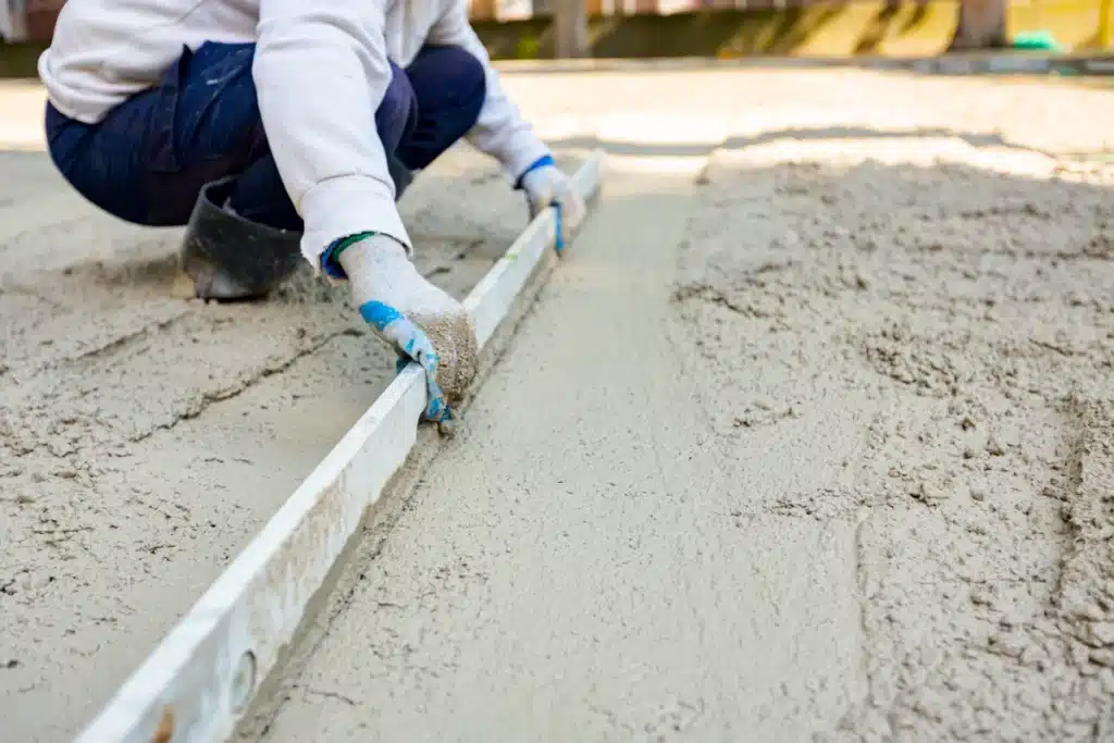 Worker leveling concrete slab after slabjacking lift in Garland, TX