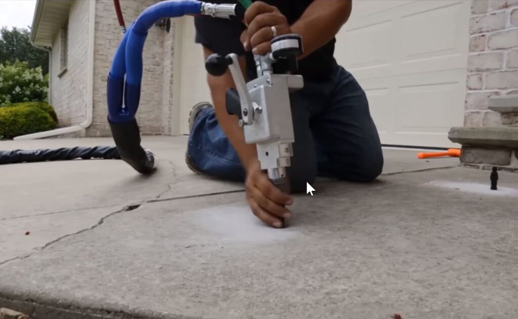 Contractor performing polyurethane foam injection on residential driveway in Garland, TX