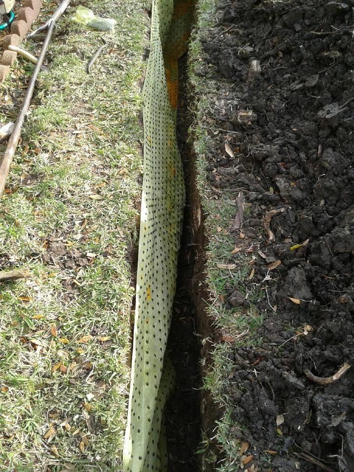 Close-up of perforated root barrier material installed in trench in Garland, TX