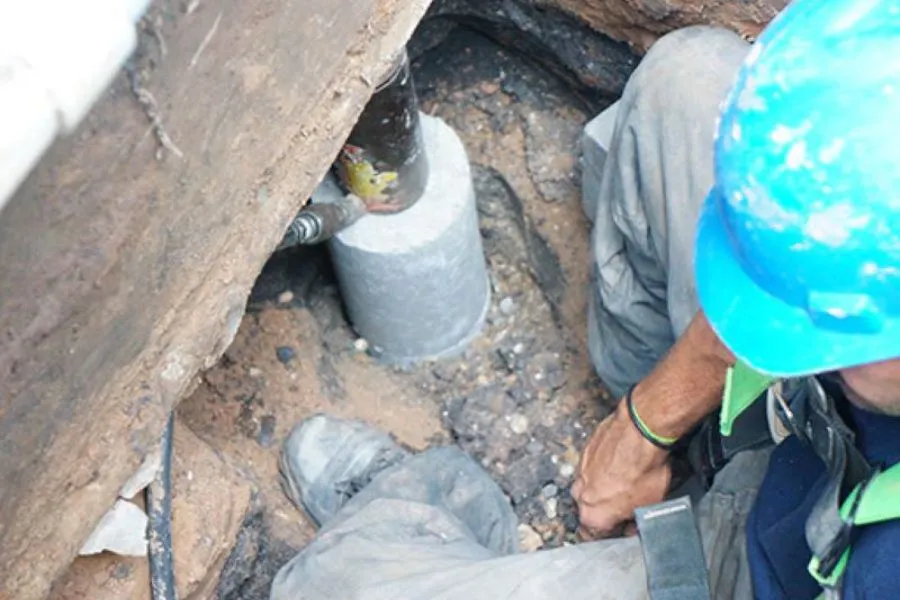 Contractor installing slab pier beneath home foundation in Garland, TX