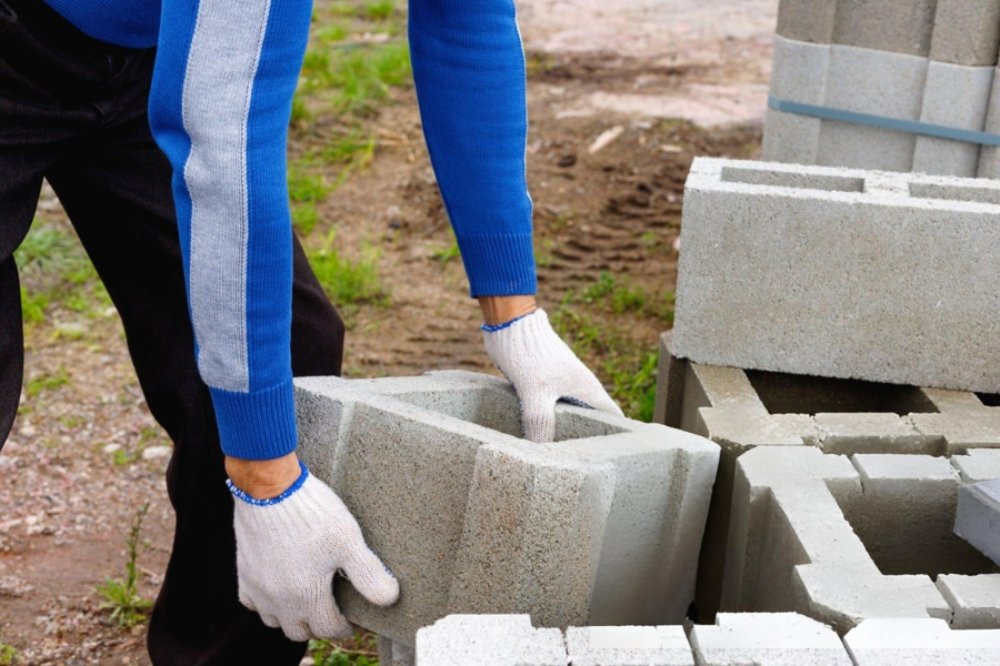 Contractor installing concrete block with grout for structural foundation work in Garland, TX